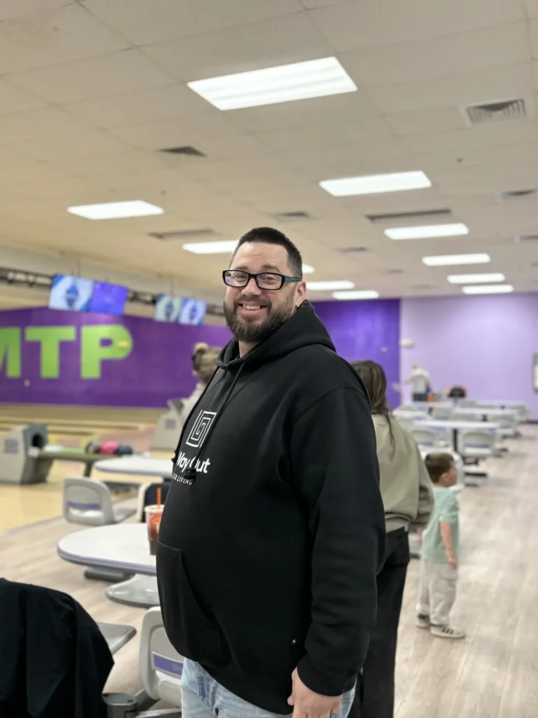 Smiling man in a black hoodie at the Nashoba Springs bowling outing