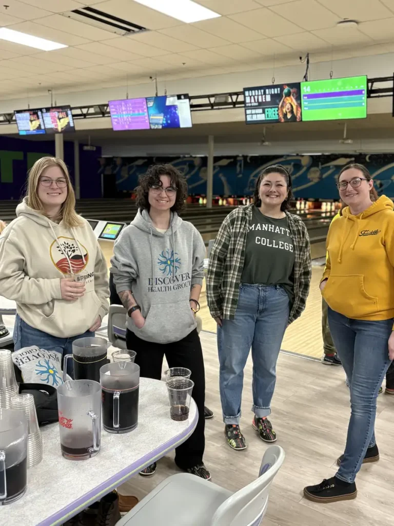 Four women in hoodies smiling by the lanes at the Nashoba Springs bowling outing