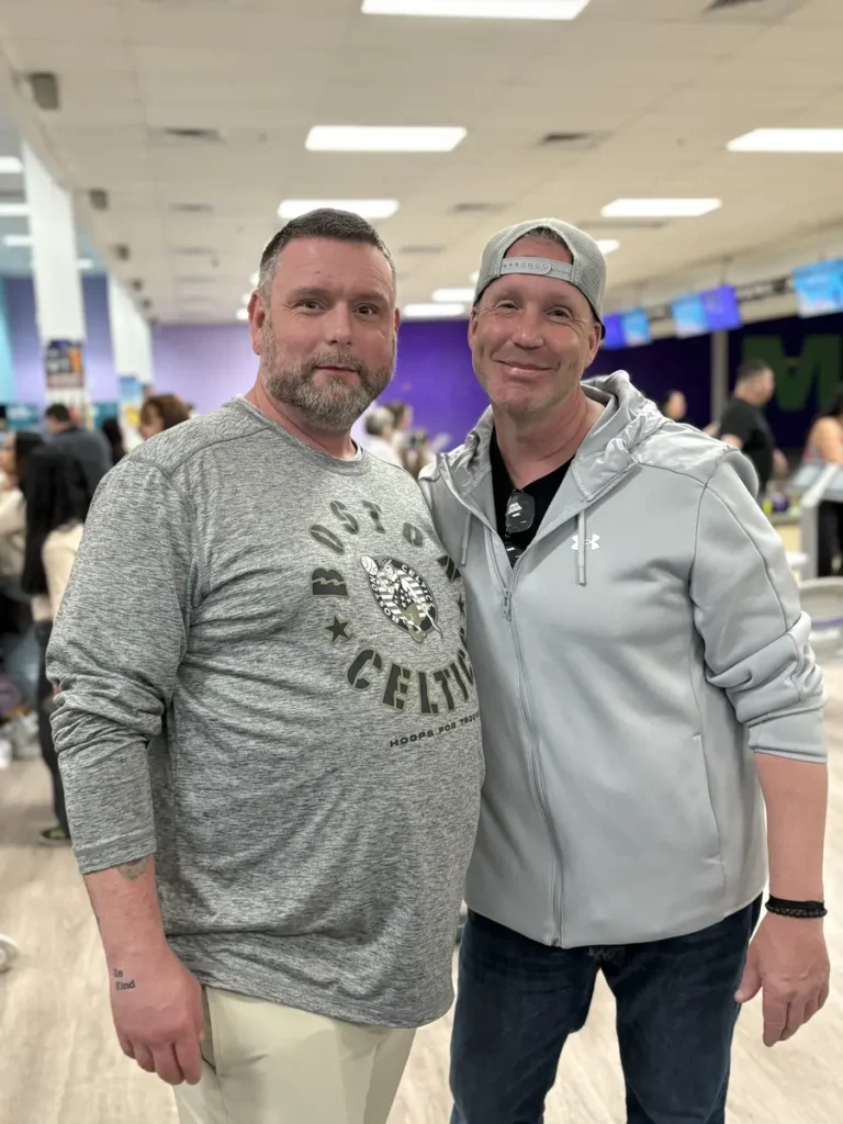 Two men smiling side by side at the Nashoba Springs bowling outing