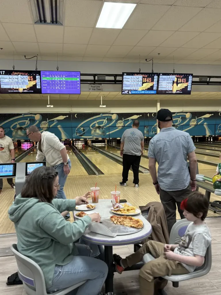 Guests sharing pizza at a table during the Nashoba Springs bowling outing