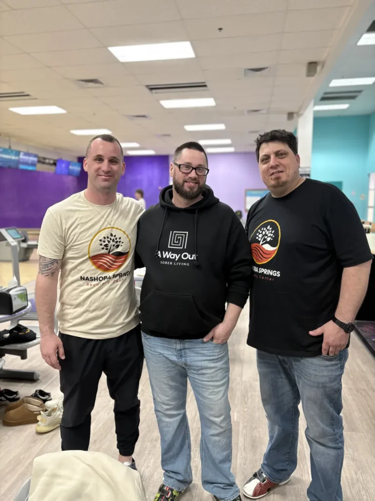 Three men in Nashoba Springs shirts posing at the bowling outing