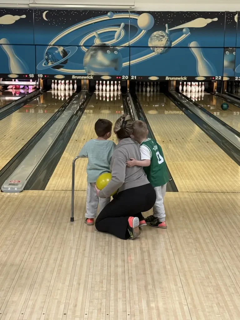 Adult helping a child bowl at the Nashoba Springs bowling outing