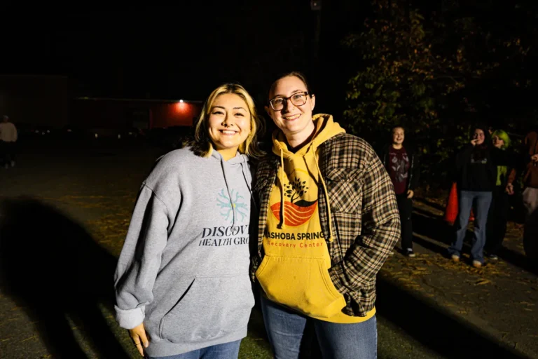 Two women in Nashoba Springs hoodies smiling at the Fright Kingdom outing