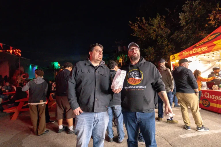 Two men in Nashoba Springs hoodies near the food stands at Fright Kingdom