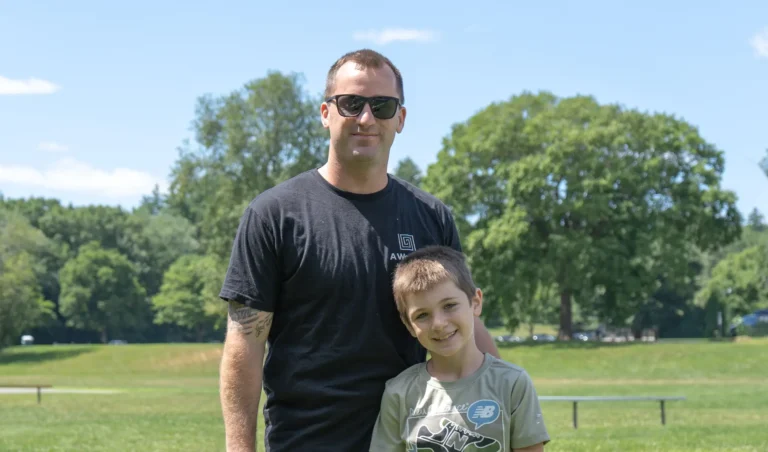 Man and boy smiling in the park at the Nashoba Springs kickball outing