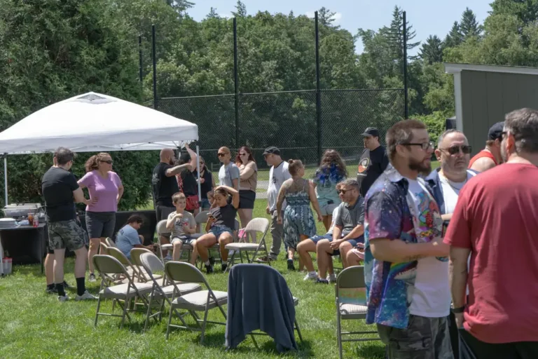 Families relaxing under a canopy at the Nashoba Springs kickball outing