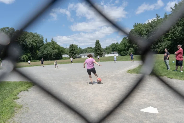 Kickball game seen through a chain-link fence