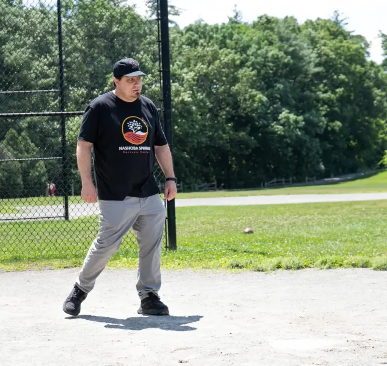 Man in a Nashoba Springs shirt pitching at the kickball outing