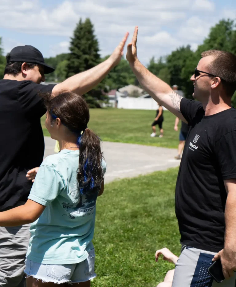 Adult and child sharing a high five at the Nashoba Springs kickball outing