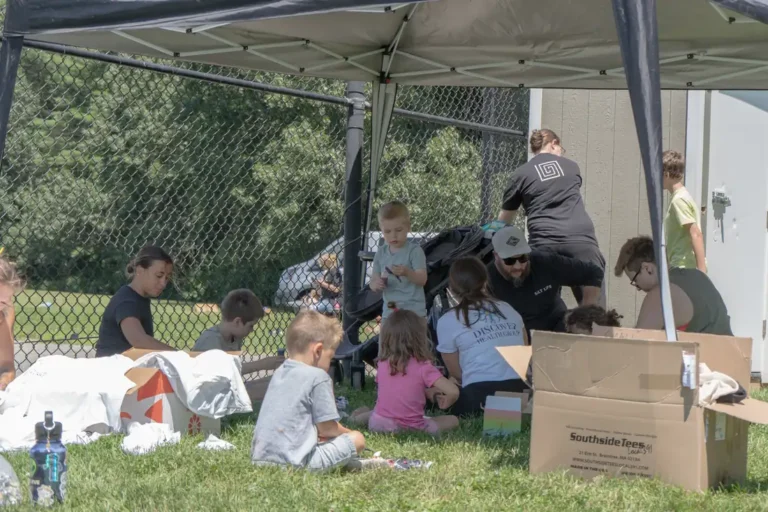 Kids and adults resting in the shade at the Nashoba Springs kickball outing