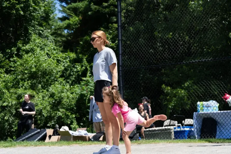 Girl kicking the ball while a woman watches at the Nashoba Springs kickball outing