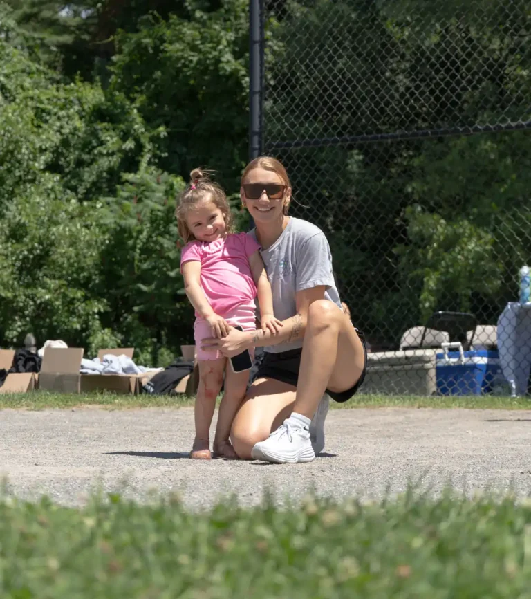 Woman and girl posing on the field at the Nashoba Springs kickball outing