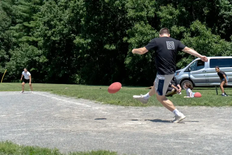 Man kicking the ball high at the Nashoba Springs kickball outing